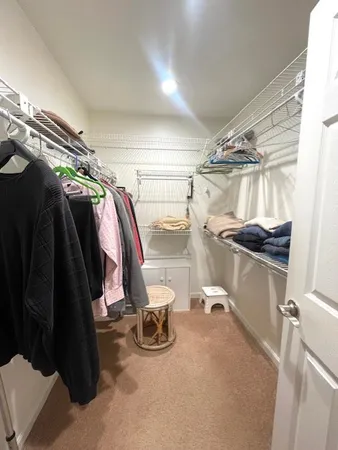 a view of walk in closet with clothes and shoes