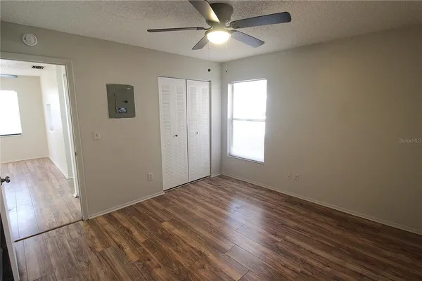 an empty room with wooden floor a ceiling fan and closet