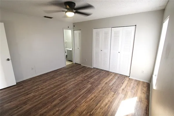a view of empty room with wooden floor and fan