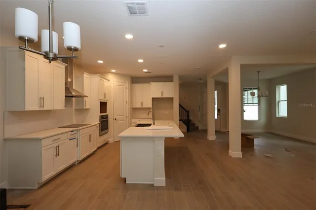 a kitchen with stainless steel appliances kitchen island hardwood floor sink and stove