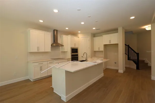 a large kitchen with stainless steel appliances a large counter top and a stove