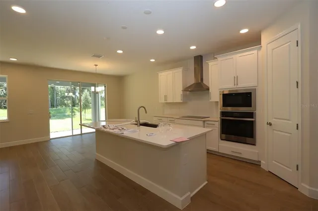 a kitchen with stainless steel appliances granite countertop a sink and a stove top oven with wooden floor