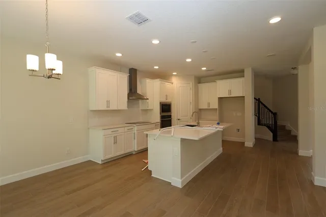 a large white kitchen with a refrigerator a sink dishwasher and white cabinets with wooden floor