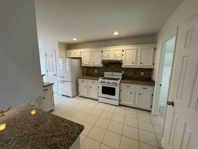 a kitchen with white cabinets a sink a stove a microwave and cabinetry