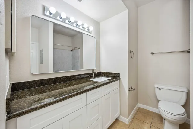 a bathroom with a granite countertop sink a toilet and mirror