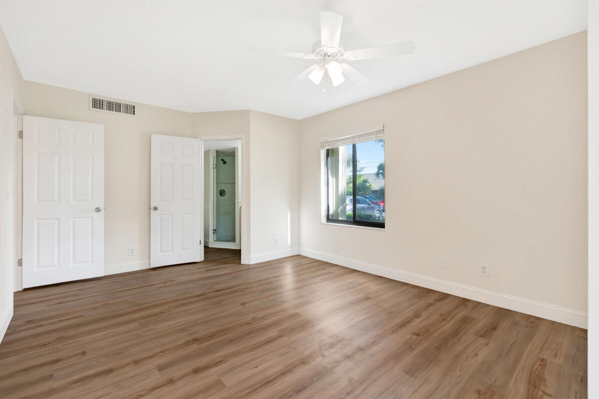 150 Pineview Road, Unit L3 Jupiter, FL 33469 - Photo 4 of 12 an empty room with wooden floor chandelier fan and windows