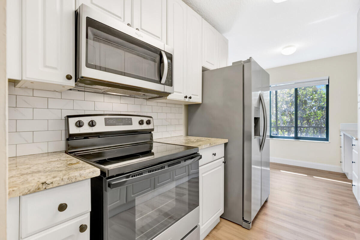 150 Pineview Road, Unit L3 Jupiter, FL 33469 - Photo 6 of 12 a kitchen with granite countertop cabinets stainless steel appliances and wooden floor