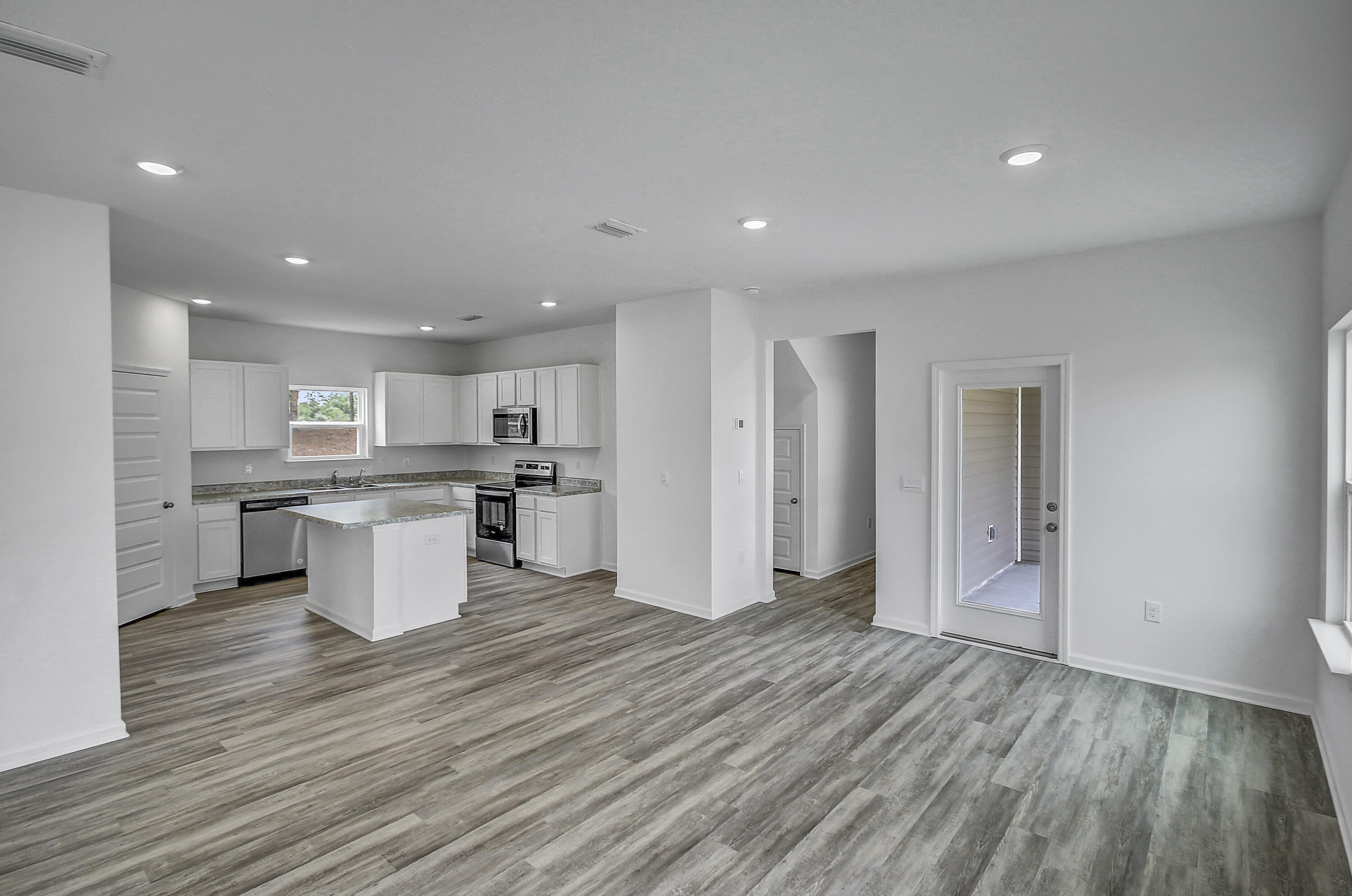 247 Staggerbush Street Freeport, FL 32439 - Photo 4 of 36 an open kitchen with white cabinets and stainless steel appliances
