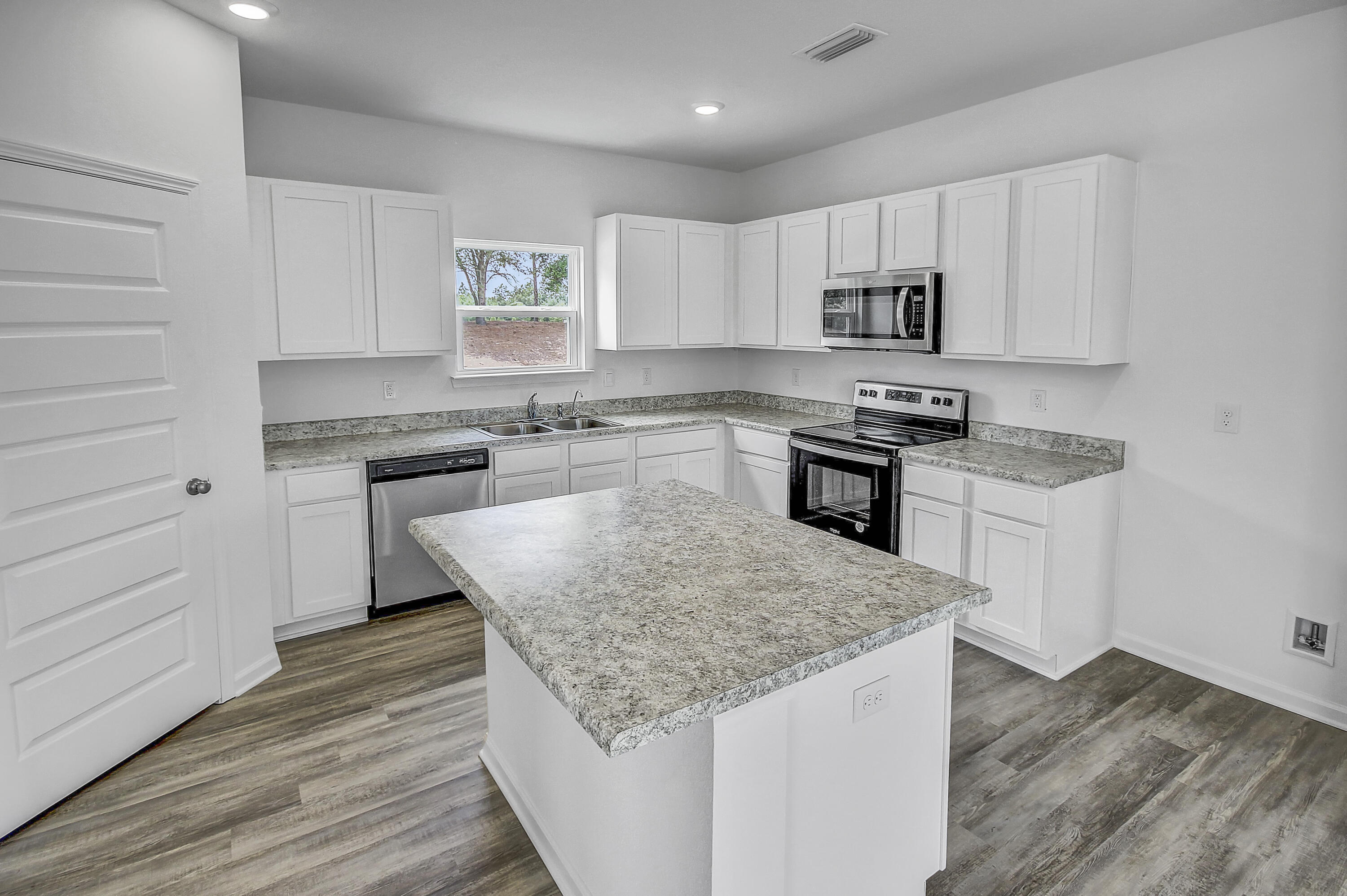 247 Staggerbush Street Freeport, FL 32439 - Photo 5 of 36 a kitchen with stainless steel appliances granite countertop a stove top oven a refrigerator a sink and dishwasher with wooden floor