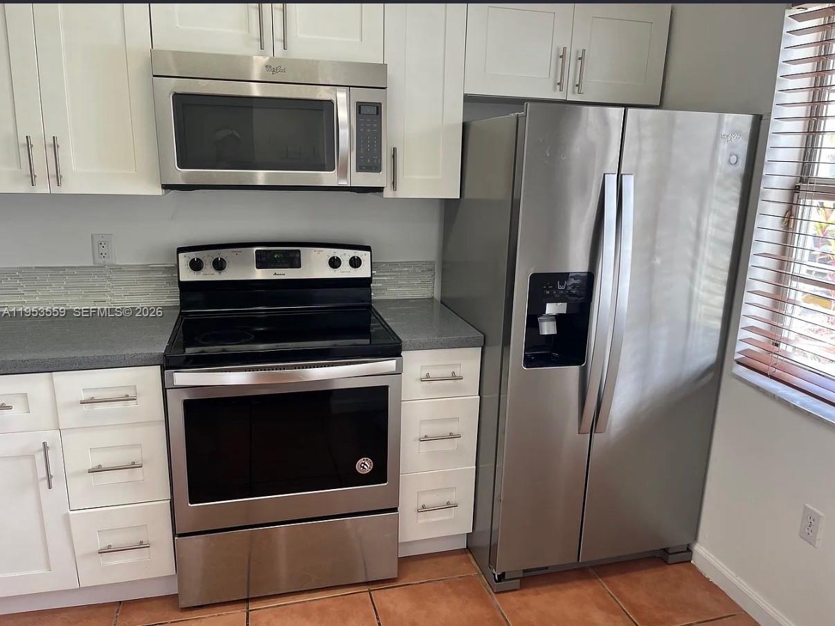 14212 Southwest 121st Place, Unit 6 Miami, FL 33186 - Photo 11 of 19 a kitchen with stainless steel appliances white cabinets a refrigerator and a stove