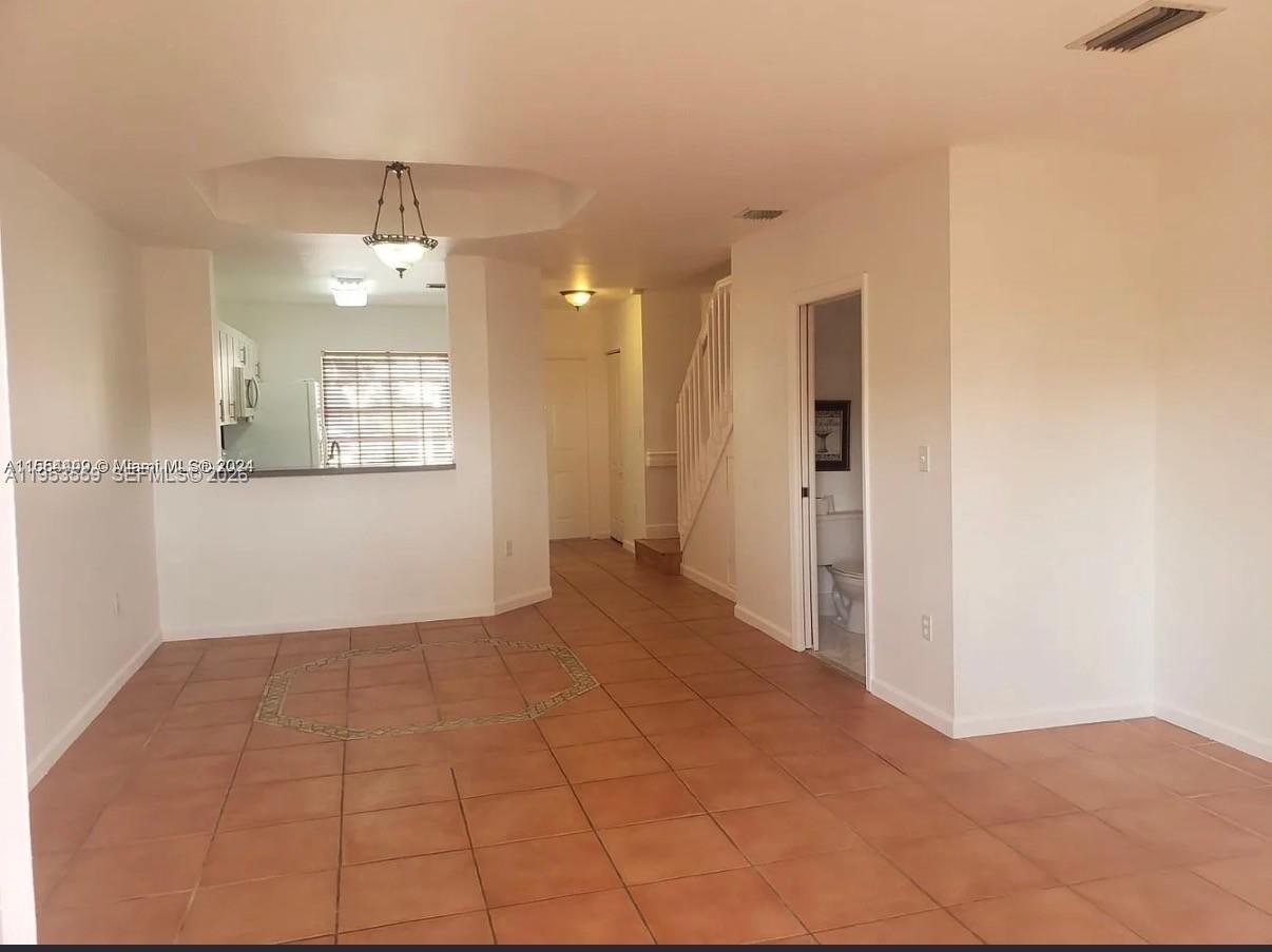 14212 Southwest 121st Place, Unit 6 Miami, FL 33186 - Photo 12 of 19 an empty room with chandelier fan and kitchen view