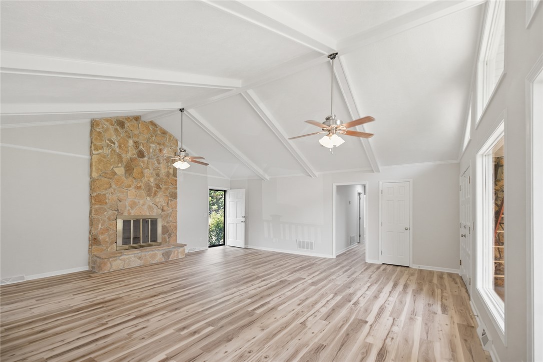 902 Cherokee Road Pelzer, SC 29669 - Photo 7 of 38 A spacious living room features vaulted ceilings, light wood flooring, and a floor-to-ceiling stone fireplace.