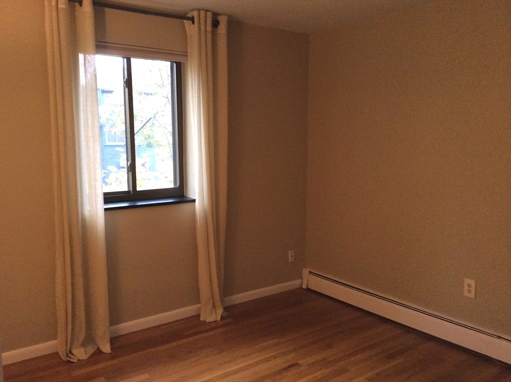 5 Centre Street, Unit 42 Cambridge, MA 02138 - Photo 6 of 10 an empty room with wooden floor and windows