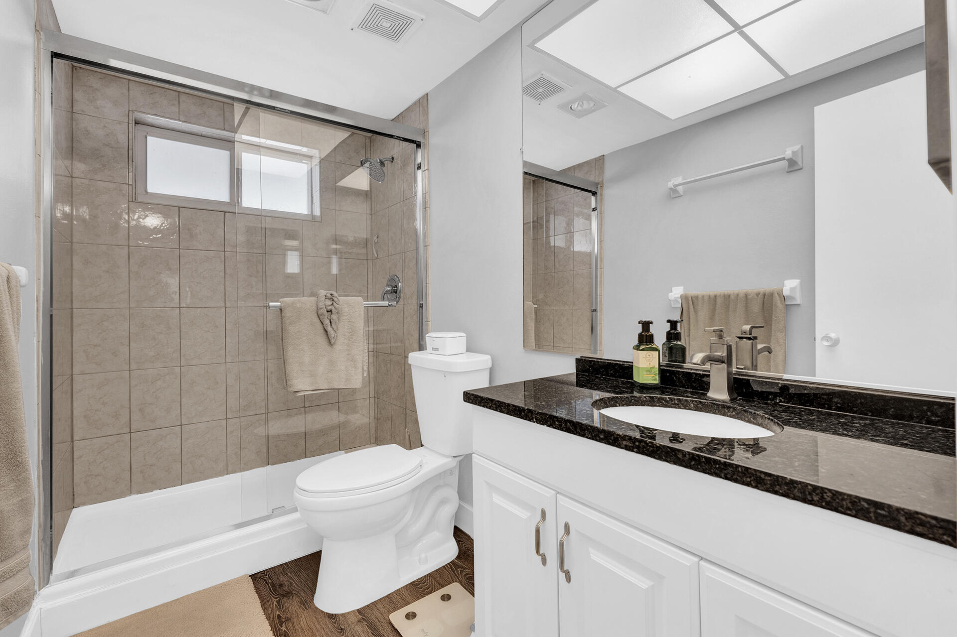 6100 Northeast 7th Avenue, Unit 20 Boca Raton, FL 33487 - Photo 32 of 42 a bathroom with a granite countertop sink a toilet a mirror and shower