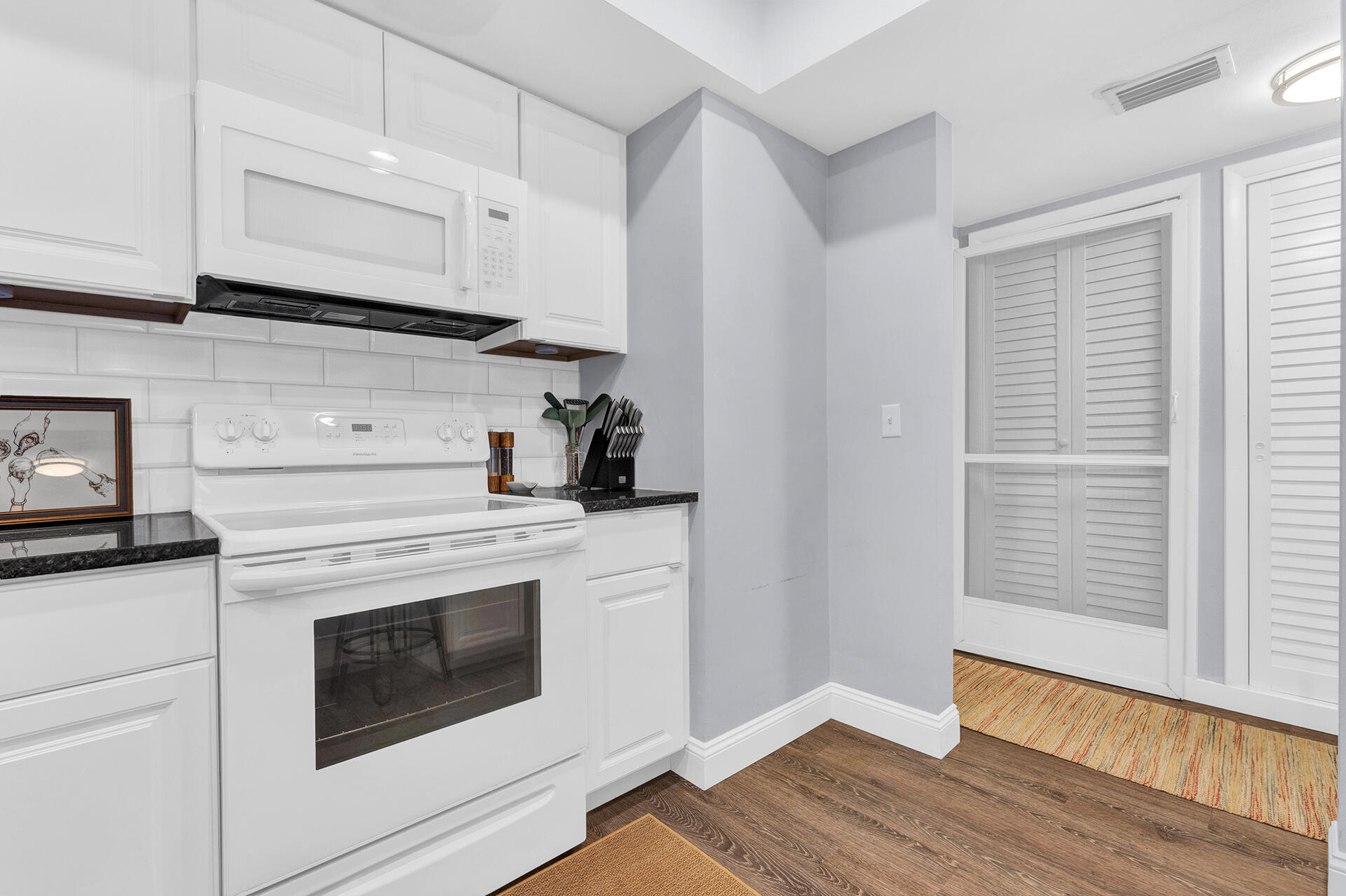 6100 Northeast 7th Avenue, Unit 20 Boca Raton, FL 33487 - Photo 8 of 42 a kitchen with granite countertop white cabinets and white appliances