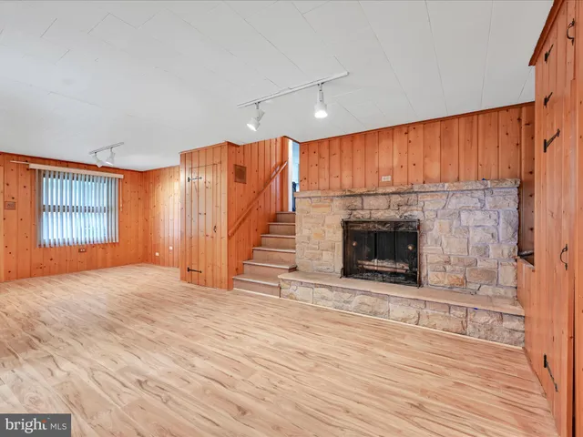 an empty room with wooden floor fireplace and windows