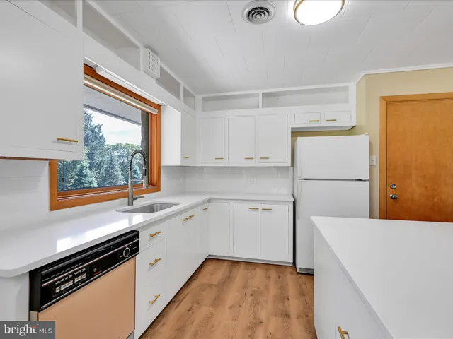 a kitchen with a refrigerator a stove a sink dishwasher and white cabinets with wooden floor