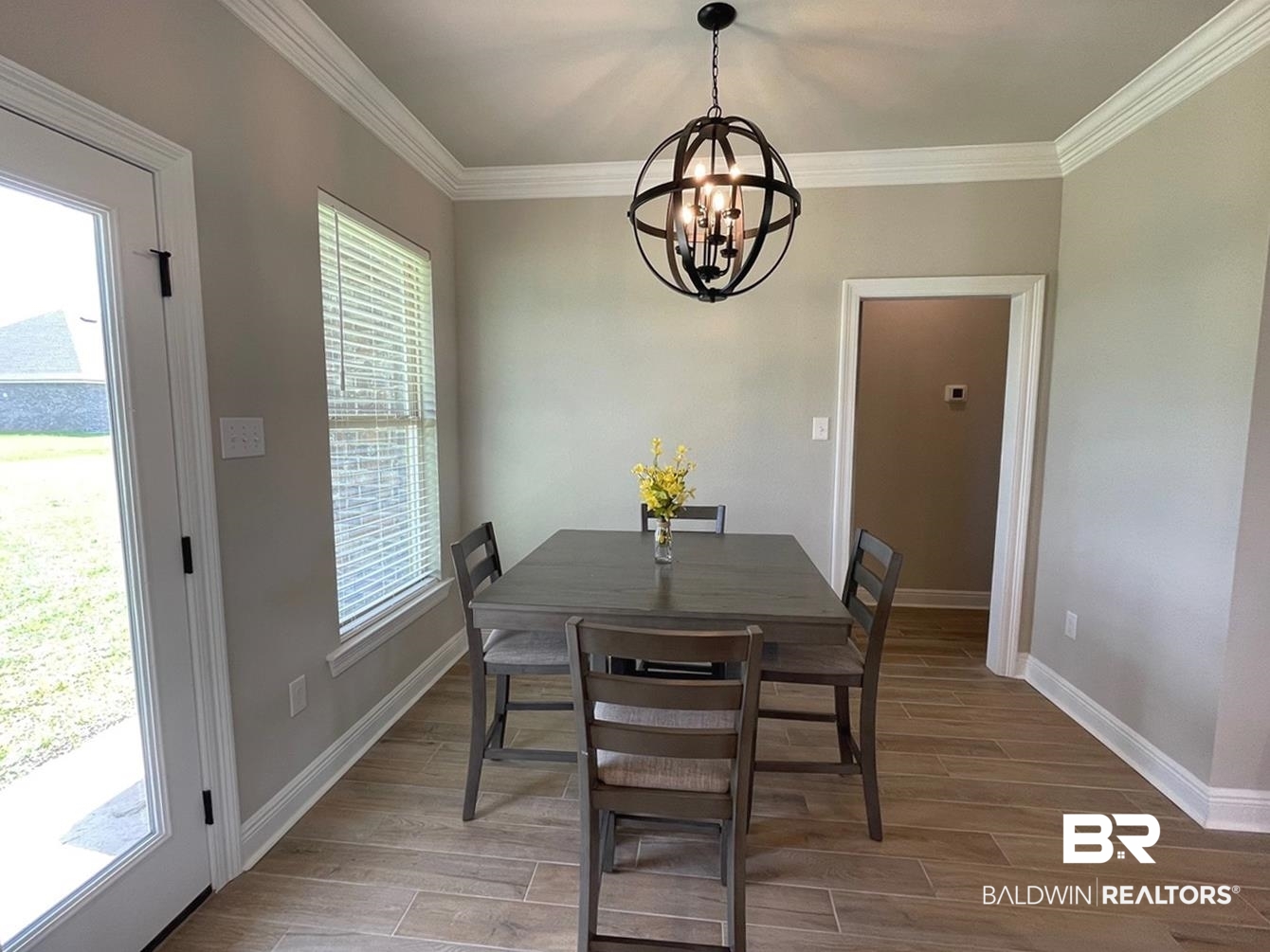 9961 Chipper Lane Foley, AL 36535 - Photo 6 of 16 Dining area with a chandelier, crown molding, hardwood / wood-style flooring, and a healthy amount of sunlight