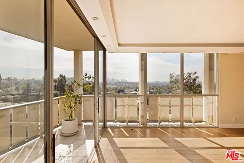 a large white kitchen with stainless steel appliances granite countertop a stove and a large window