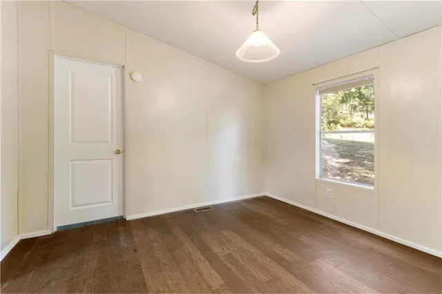 an empty room with wooden floor and mirror