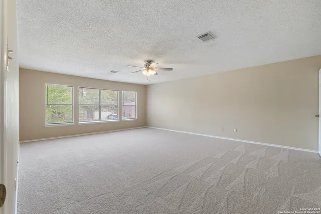 an empty room with windows and chandelier fan