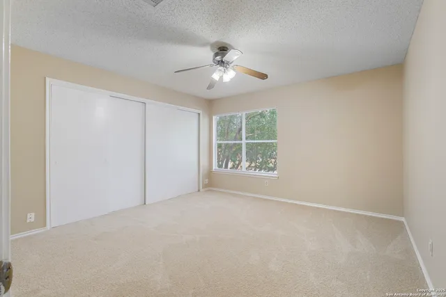 an empty room with windows and fan