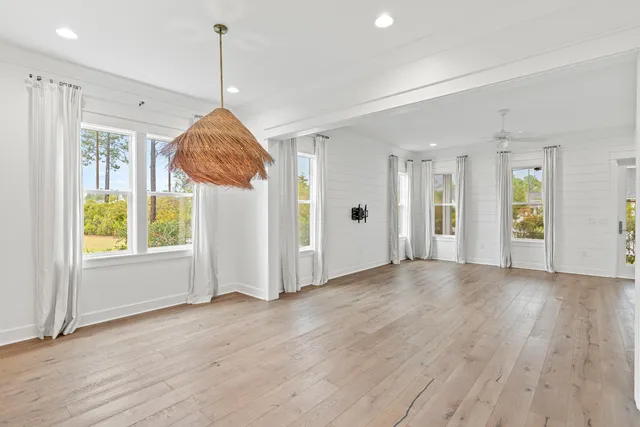 a view of an empty room with wooden floor and windows