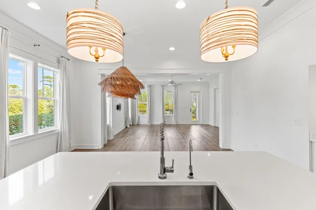 a kitchen with stainless steel appliances granite countertop a sink a stove a refrigerator and white cabinets with wooden floor