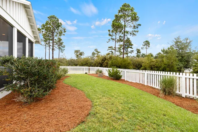 a view of a yard in front of a house with plants and large tree