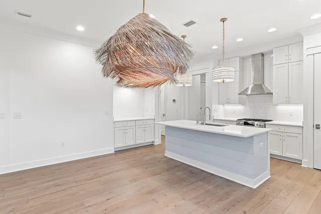 a kitchen with stainless steel appliances a stove a sink and white cabinets with wooden floor