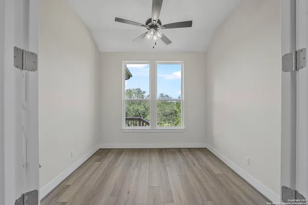 an empty room with windows and a ceiling fan