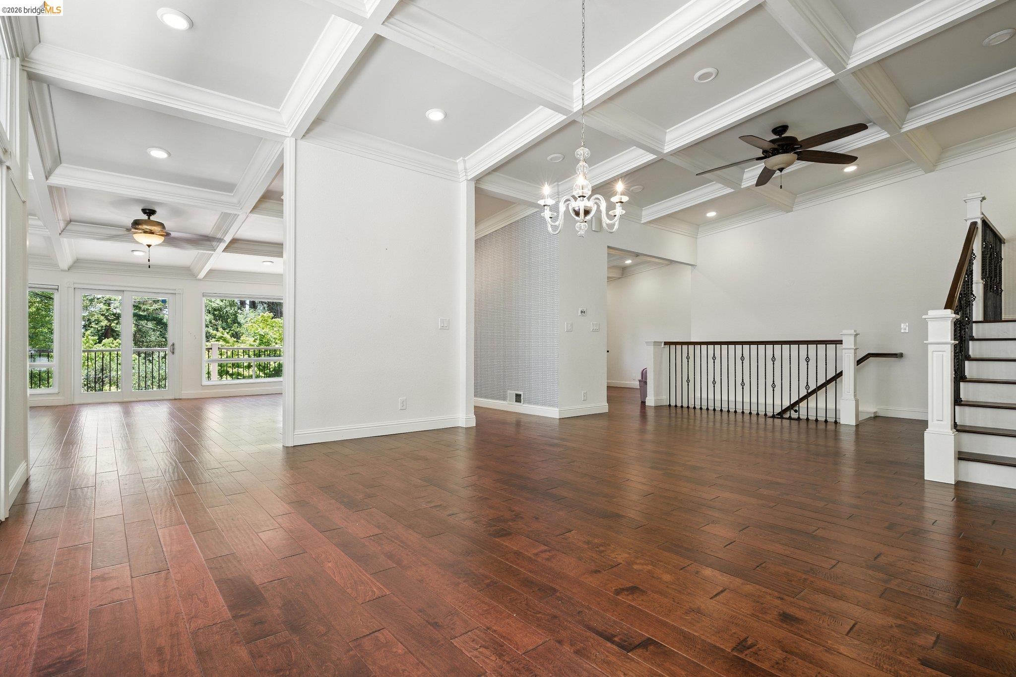 18 Conrad Court Oakland, CA 94611 - Photo 11 of 36 Unfurnished living room with a ceiling fan, coffered ceiling, beamed ceiling, dark wood-style floors, and a chandelier