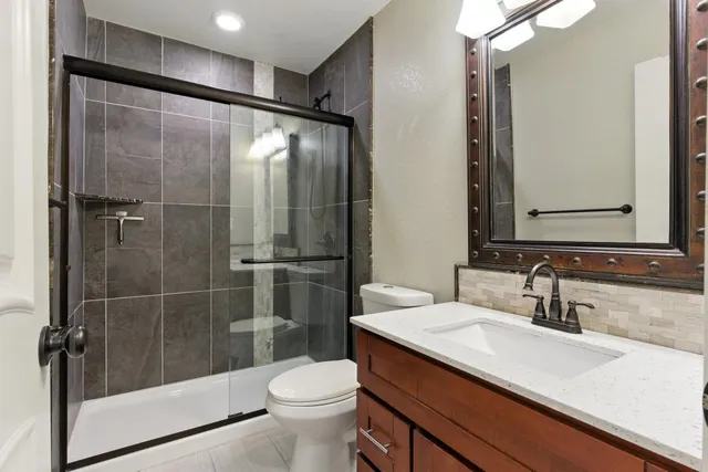 a bathroom with a shower sink vanity mirror and toilet