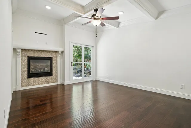 an empty room with wooden floor a fireplace a ceiling fan and windows