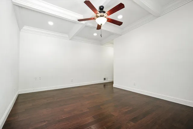 an empty room with wooden floor and ceiling fan