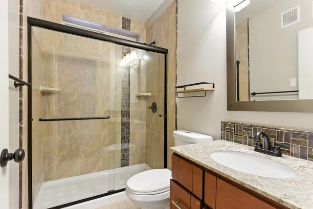 a bathroom with a granite countertop sink toilet and shower