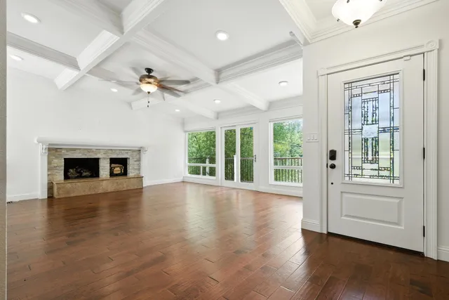 an empty room with wooden floor chandelier and fireplace