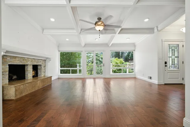 a view of an empty room with wooden floor fireplace and a window