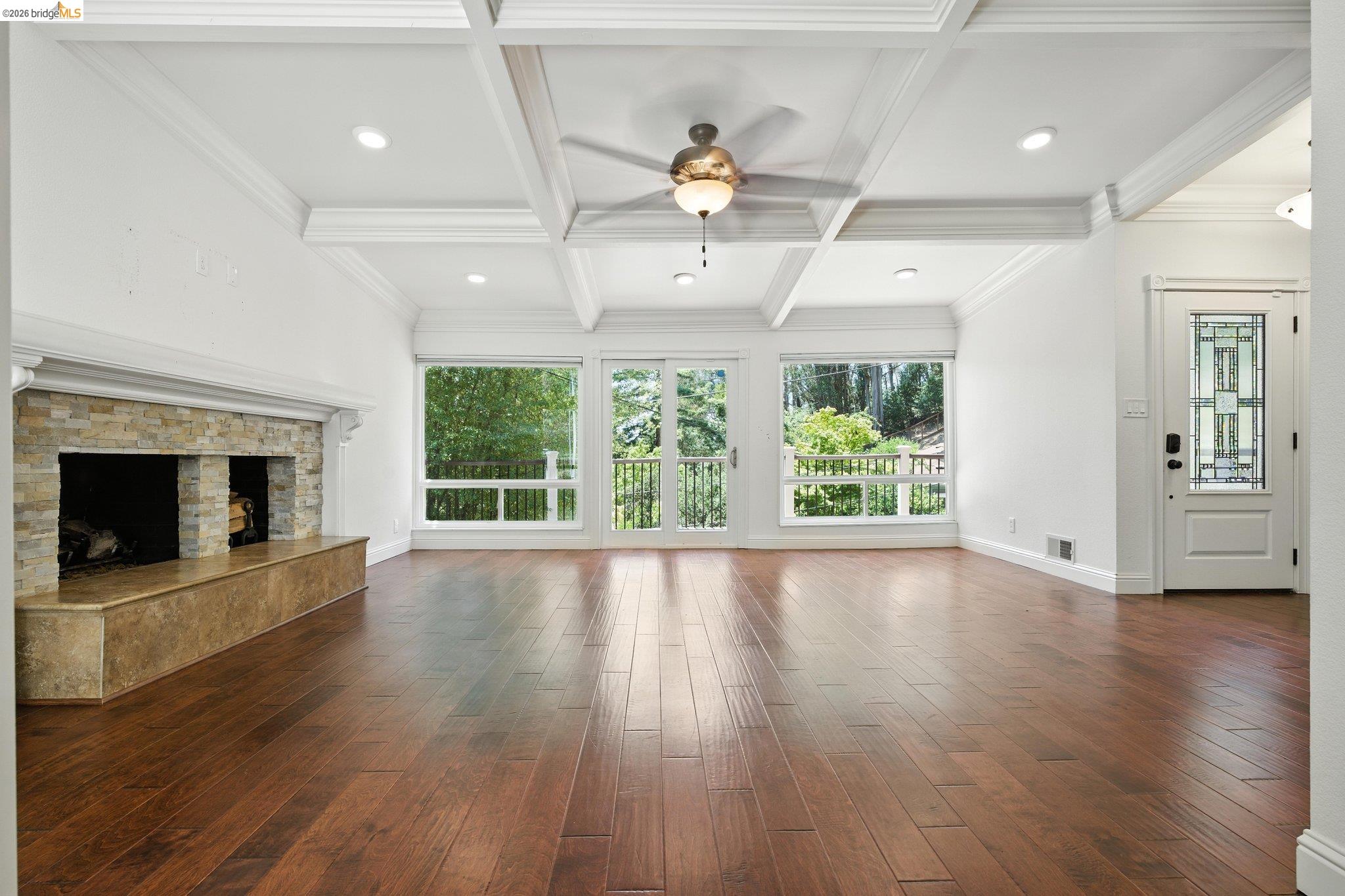 18 Conrad Court Oakland, CA 94611 - Photo 9 of 36 Unfurnished living room featuring a fireplace, dark wood-type flooring, coffered ceiling, beamed ceiling, and ceiling fan