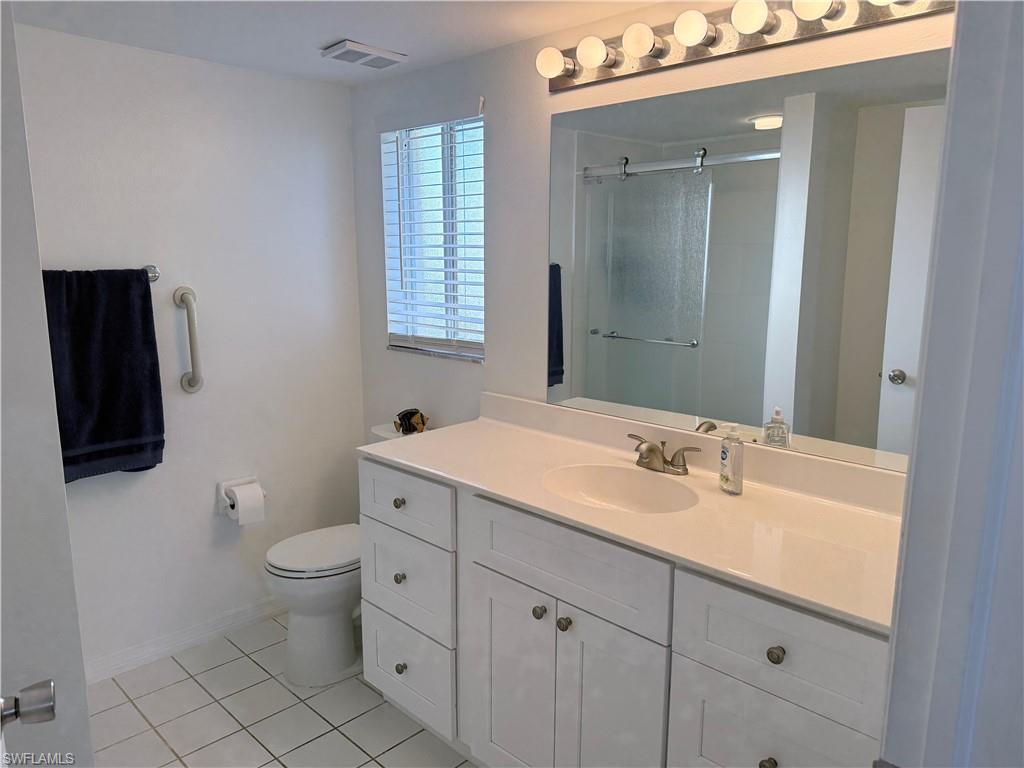 7750 Jewel Lane, Unit 101 Naples, FL 34109 - Photo 18 of 28 a spacious bathroom with a double vanity sink a mirror and a toilet