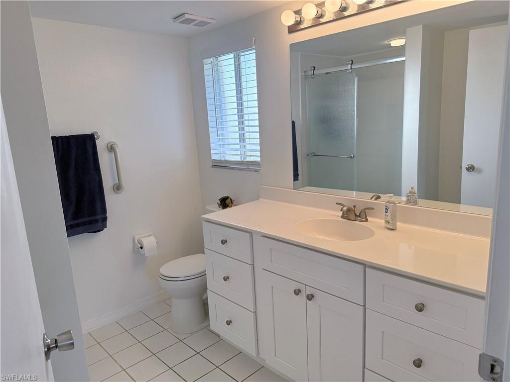 7750 Jewel Lane, Unit 101 Naples, FL 34109 - Photo 19 of 28 a bathroom with a toilet a sink a mirror a window and vanity