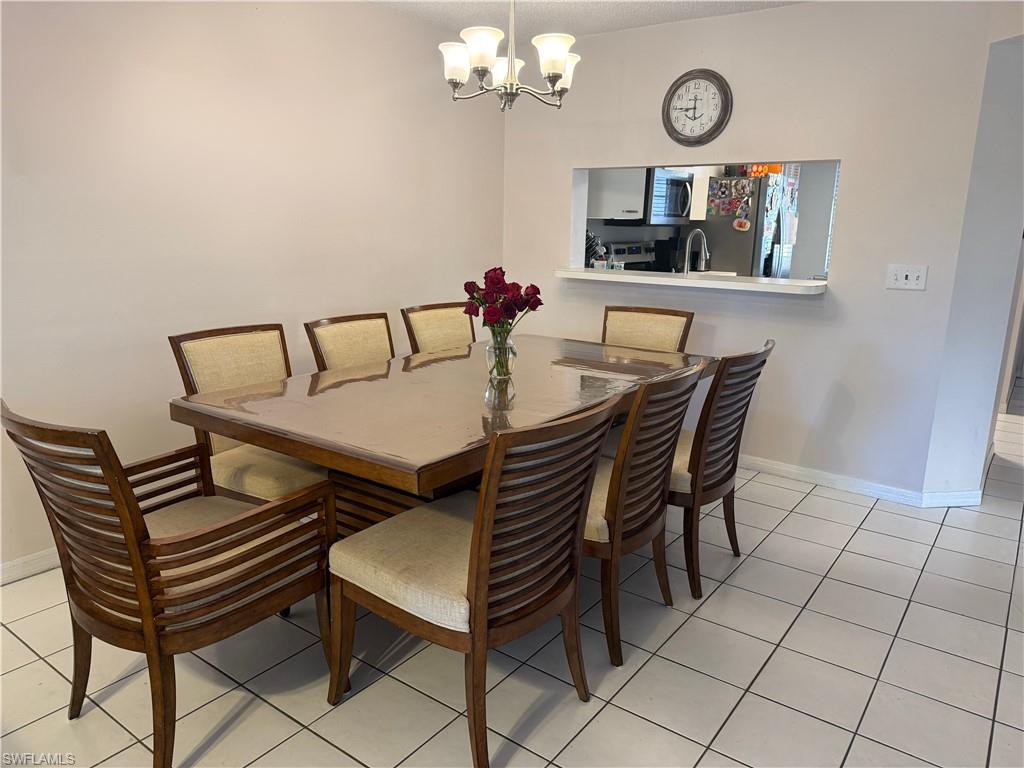 7750 Jewel Lane, Unit 101 Naples, FL 34109 - Photo 10 of 28 a view of a dining room with furniture and a chandelier