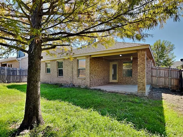 a view of a house with a yard and a large tree