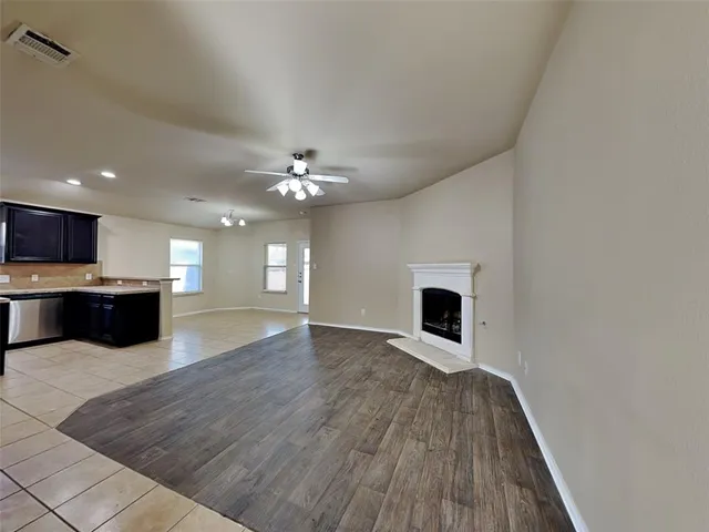 a living room with stainless steel appliances kitchen island a chandelier and wooden floor
