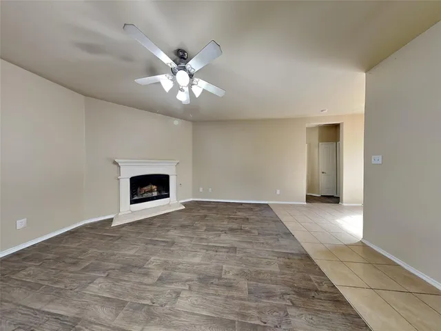 a view of an empty room with chandelier fan and fire place