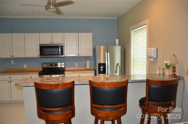 a kitchen with stainless steel appliances granite countertop a stove a refrigerator a sink a dining table and chairs