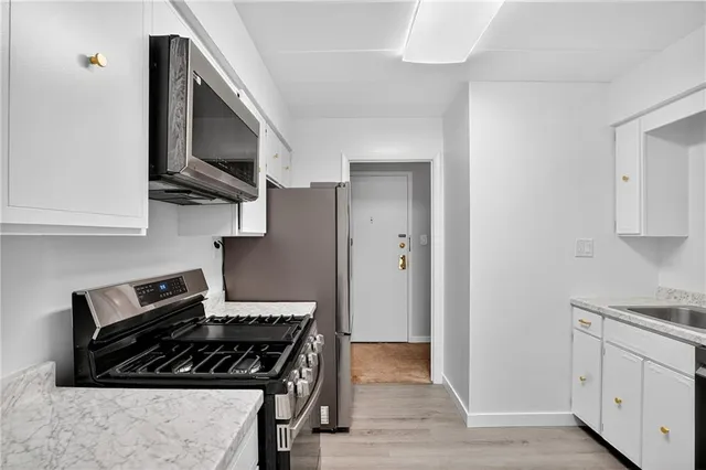 a kitchen with stainless steel appliances granite countertop a sink a stove and a refrigerator