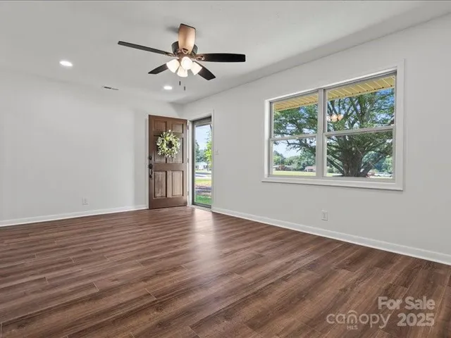 a view of an empty room with wooden floor and a window