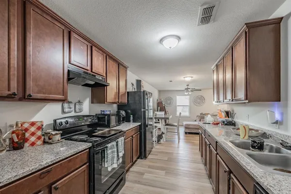 a kitchen with stainless steel appliances granite countertop sink stove top oven and cabinets