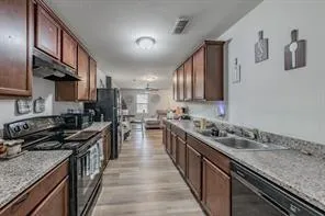 a kitchen with stainless steel appliances granite countertop a stove top oven a sink a counter space and cabinets